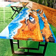 a table with an artistic design on it sitting in the grass next to a wooden fence