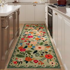 a floral rug in the middle of a kitchen with white cabinets and counter tops on both sides