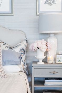 a bedroom with two pictures on the wall and a nightstand with flowers in front of it