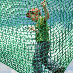 a young boy riding a skateboard on top of a net covered in green netting