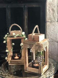 two wooden lanterns sitting on top of a glass table next to a fire place filled with candles