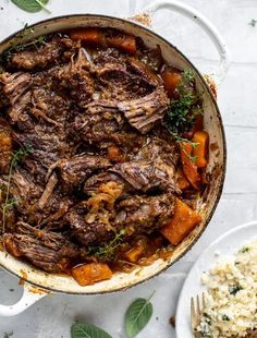 a pot filled with meat and vegetables next to a plate of rice on a table