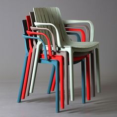 four different colored plastic chairs sitting next to each other on a gray surface with no one around them