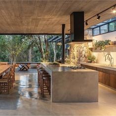 an open kitchen and dining room area with stone walls, floor to ceiling windows, and wooden furniture