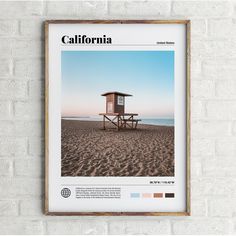 a white brick wall with a wooden frame displaying a photo of a lifeguard hut on the beach