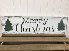 a merry christmas sign sitting on top of wooden pallets in front of a white wall