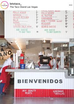 a man standing in front of a counter with food on it and menus hanging from the ceiling