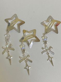 three pairs of earrings with star charms hanging from the side on a white table top