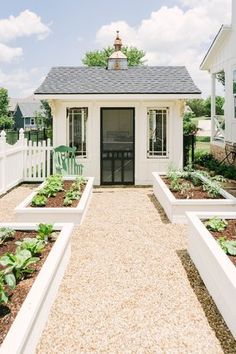 a small white house with lots of plants in the front yard