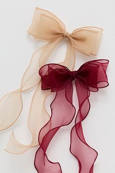 two ribbons tied to each other on a white surface, one with a red bow