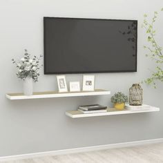 a flat screen tv mounted to the side of a wall next to a vase with flowers