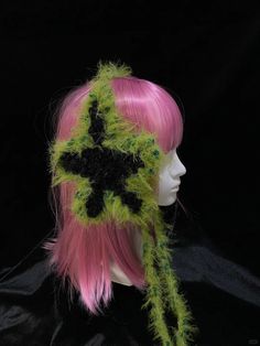 a mannequin head wearing a green and black crocheted hat with flowers on it