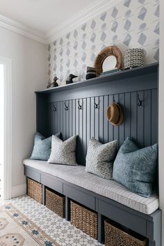 a bench with some pillows on top of it next to a wall mounted coat rack