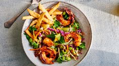 a white plate topped with shrimp and french fries next to a glass of orange juice