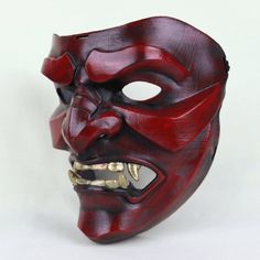 a red mask with gold teeth on it's face is shown in front of a white background