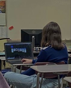 two people sitting at desks with laptop computers in front of them and one person standing up