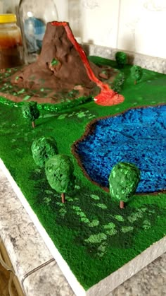 a cake made to look like a pond with trees and rocks on the ground next to it