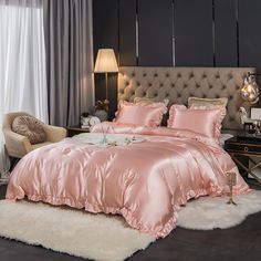 a bed with pink comforter and pillows in a bedroom next to a window,