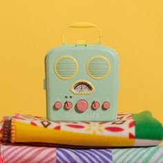 an old fashioned radio sitting on top of some folded towels and other colorful items in front of a yellow background