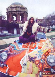 a woman sitting on top of an orange car