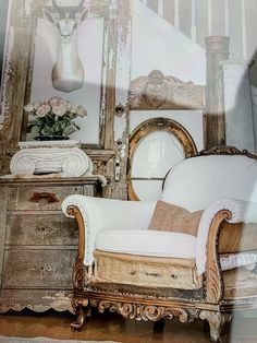 an antique chair and mirror in front of a wooden dresser with antelope head on the wall