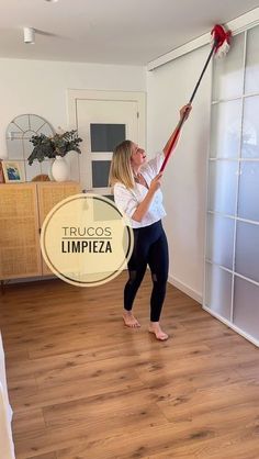 a woman is holding a broom in her hand while standing on the hardwood floor next to a sliding glass door