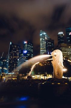 the water spewing out from the fountain is lit up in the city at night