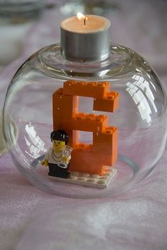 a lego man is in a glass ball with a candle on the table next to it