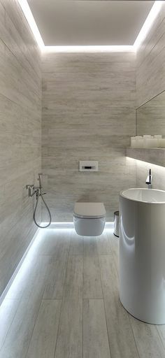 a white toilet sitting next to a sink in a bathroom under a light filled ceiling