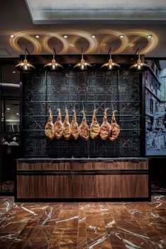 some meat hanging from the ceiling in front of a black wall with lights on it