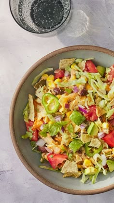 a salad in a bowl next to a glass of water