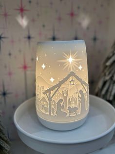 a lighted candle holder sitting on top of a white plate next to a christmas tree