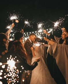 a bride and groom are surrounded by sparklers