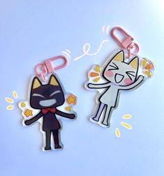 two key chains with cartoon cats attached to them on a blue surface, one has a cat and the other has a star