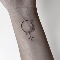 a small tattoo on the wrist of a person with a cross and flowers in it