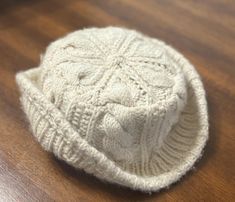 a white knitted hat sitting on top of a wooden table