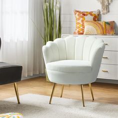 a white chair sitting on top of a wooden floor next to a black chair with gold legs