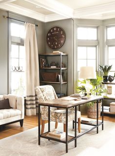 a living room filled with furniture and a large clock on the wall above it's windows