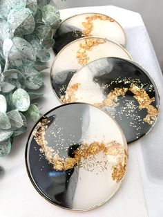 four black and white plates with gold sprinkles on them sitting on a table