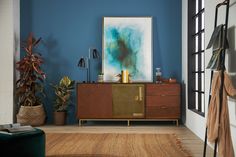 a living room with blue walls and wooden furniture in the corner, along with potted plants