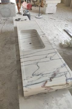 a marble sink in the middle of a room being worked on by two people standing behind it