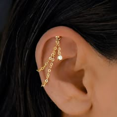 a woman's ear is adorned with gold chains