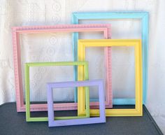 four different colored frames sitting next to each other on a black tablecloth covered surface