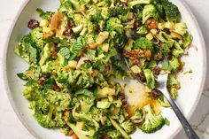 a white bowl filled with broccoli and other food on top of a table