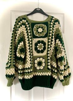 a green and white crocheted sweater hanging on a door