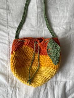 a crocheted bag with leaves on it sitting on top of a white sheet