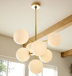 a chandelier hanging from the ceiling in a room with large windows and wooden beams