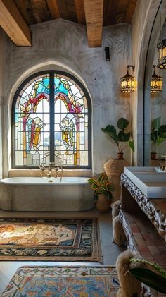 a bathroom with a tub, rugs and large stained glass window in the wall