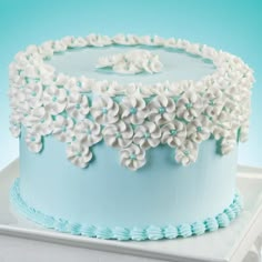 a blue and white cake with flowers on the top is sitting on a plate in front of a blue background