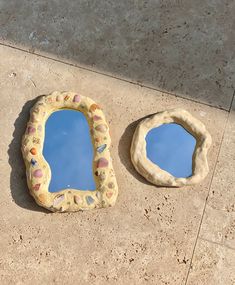 two small mirrors sitting on the ground next to each other, one is shaped like a shell